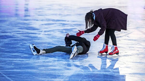 Посетители катаются на катке с искусственным льдом в парке Сокольники в Москве