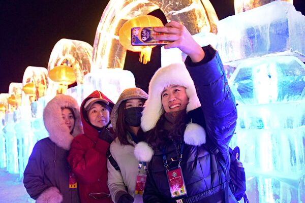 Гости фестиваля фотографируются на фоне ледяных скульптур в городе Маньчжурия