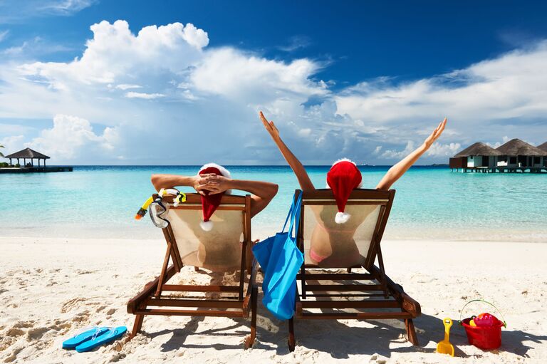 Пара в колпаках Санта Клауса на пляже на Мальдивах Пара в колпаках Санта Клауса на пляже на Мальдивах