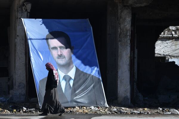 Мужчина у портрета президента Сирийской арабской республики Башара Асада на окраине сирийского Алеппо
