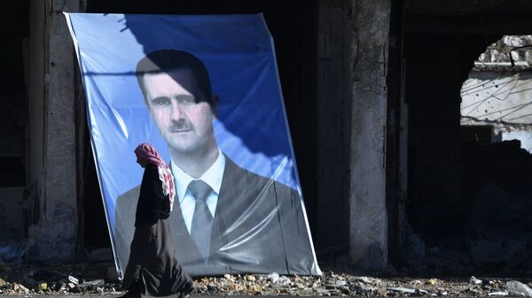 Мужчина у портрета президента Сирийской арабской республики Башара Асада на окраине сирийского Алеппо