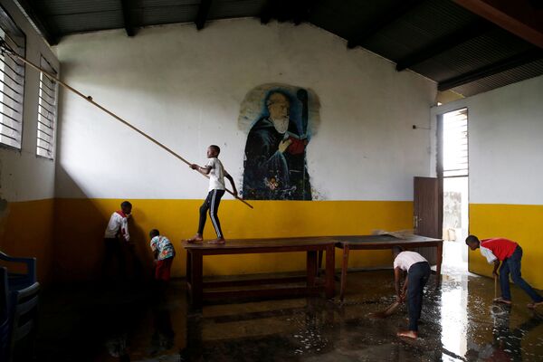 Мальчики помогают убирать церковь Святого Бенедикта во время подготовки к Рождеству в Демократической Республике Конго