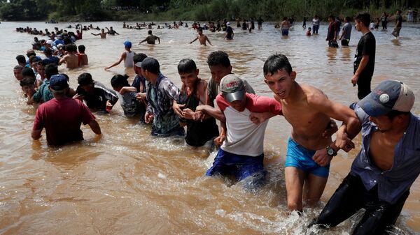 Мигранты, направляющиеся в США, пересекают реку на границе Гватемалы и Мексики