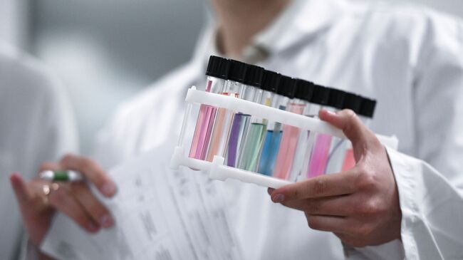 Сотрудник держит пробирки с пробами в Национальной антидопинговой лаборатории