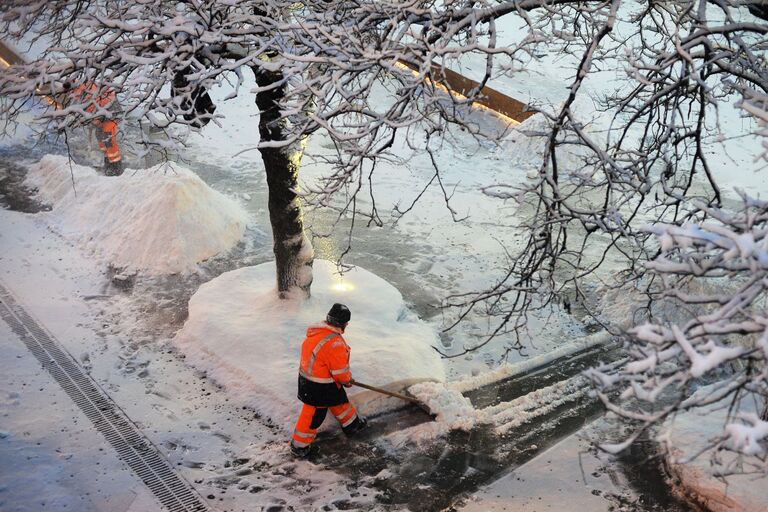 Сотрудники коммунальных служб убирают снег на улице в Москве