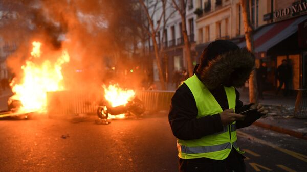 Участник протестной акции жёлтых жилетов недалеко от горящей баррикады на улице Парижа. 5 января 2018