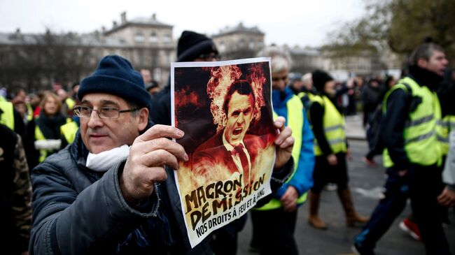 Демонстрант держит плакат во время акции желтых жилетов во Франции
