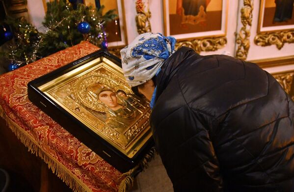 Женщина склоняется перед иконой Богоматери во время рождественского богослужения в храме святого апостола Андрея Первозванного во Владивостоке. 6 января 2019
