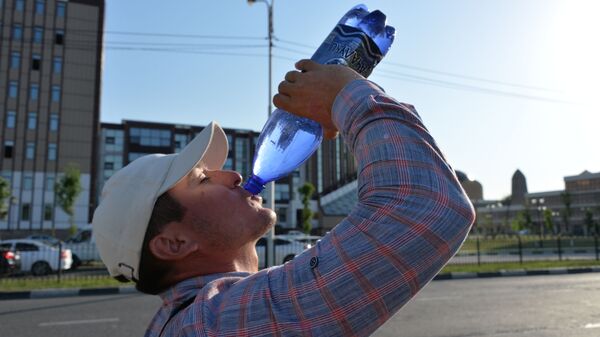 Мужчина пьет воду на жаре
