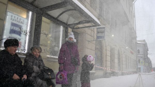 Пассажиры на остановке на Суворовском проспекте, где работники коммунальных служб убирают снег с крыш домов