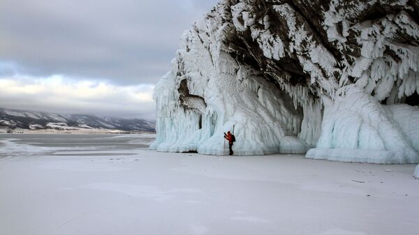 Турист катается на коньках по льду замерзшего озера Байкал