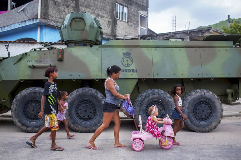 Семья проходит мимо бронетранспортера во время спецоперации в Рио-де-Жанейро, Бразилия