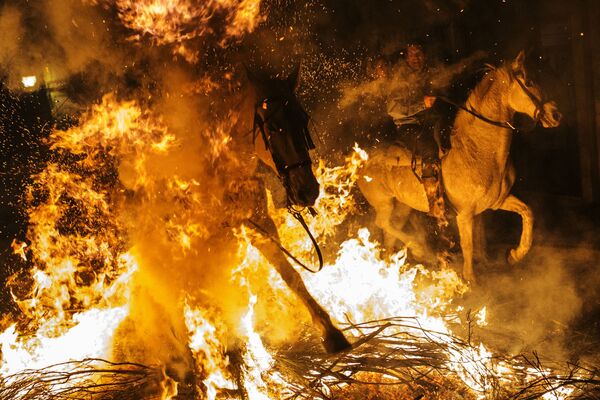 Всадники проезжают через огонь во время ежегодного фестиваля Las Luminarias в испанской деревне Сан-Бартоломе-де-Пинаре