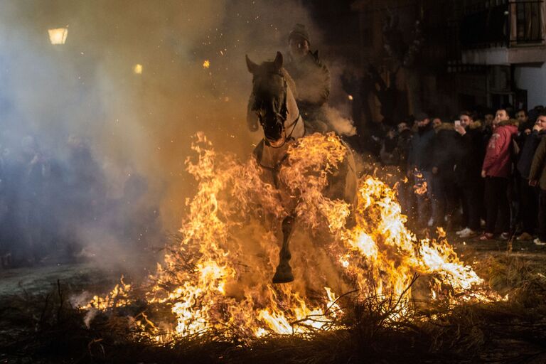 Всадник проезжает через огонь во время ежегодного фестиваля Las Luminarias в испанской деревне Сан-Бартоломе-де-Пинаре