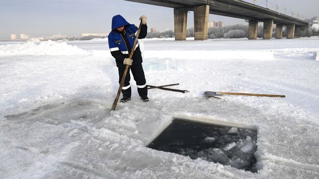 Сотрудник МЧС делает прорубь для крещенской купели на реке Обь