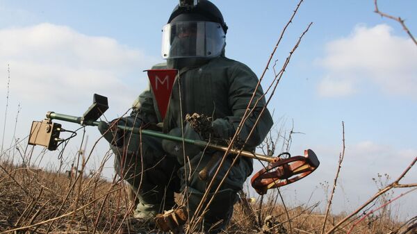Сапер инженерных войск ЮВО в защитном костюме во время разминирования местности в в Чеченской Республике