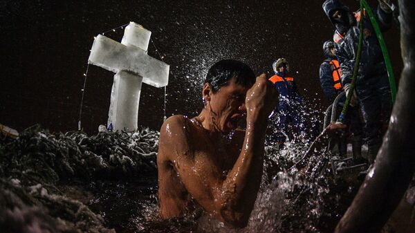 Мужчина во время традиционных купаний в праздник Крещения у храма Живоначальной Троицы в поселке Норское