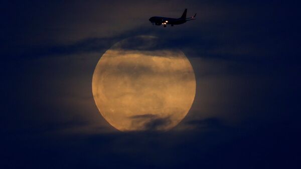 Самолет на фоне лунного затмения в небе над Сан-Диего, США