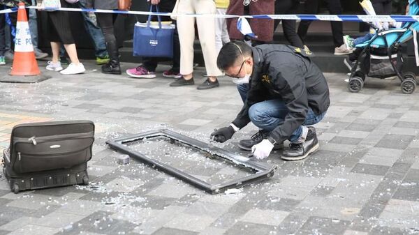 Сотрудник полиции Гонконга осматривает оконную раму, которая упала на туристку и убила ее