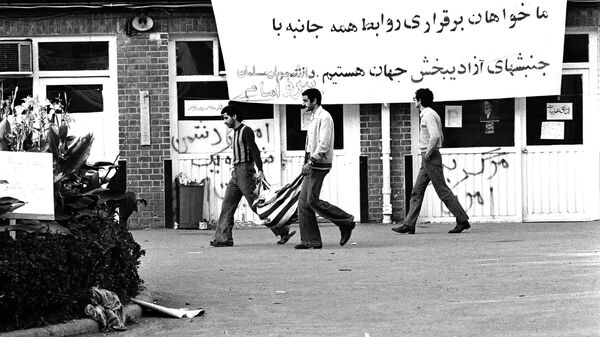 Иранцы выносят мусор на национальном флаге США из посольства в Тегеране. 13 ноября 1979