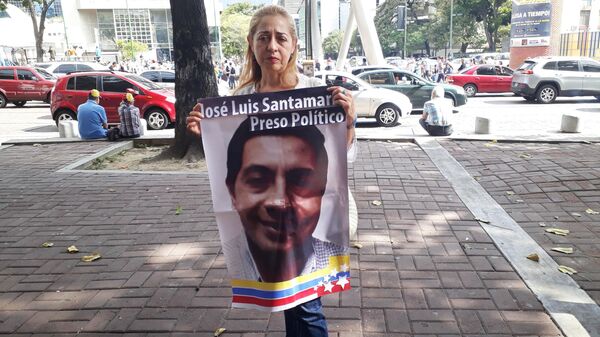 Участница митинга оппозиции в Каракасе держит плакат с изображением Хосе Луиса Сантамарии, арестованного после уличной демонстрации 2014 года. 26 января 2019