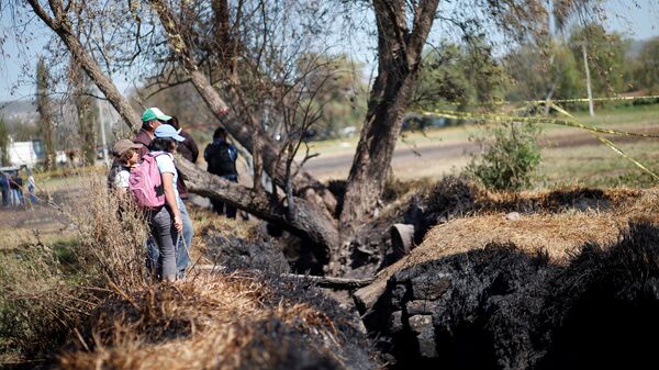 Местные жители наблюдают повреждения на месте взрыва незаконной врезки в газопровод в штате Идальго, Мексика. 21 января 2019