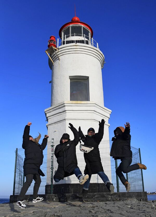 Туристы  из Республики Корея фотографируются на фоне Токаревского маяка во Владивостоке