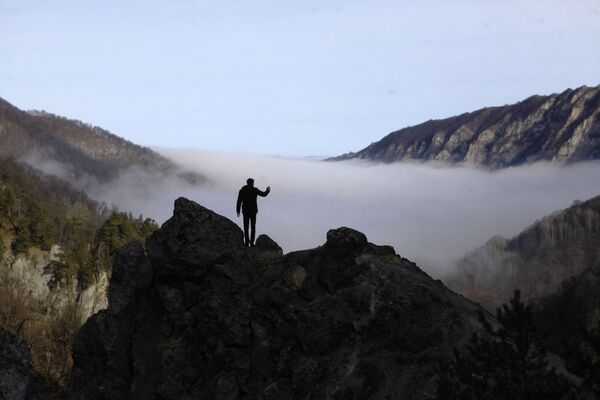 Турист фотографирует туман в ущелье горного склона Галанчожского района Чеченской республики