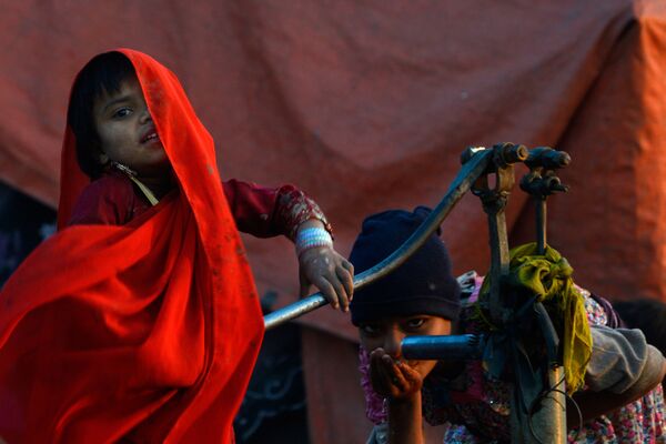 Дети пакистанских цыган пьют воду из колонки в Лахоре 