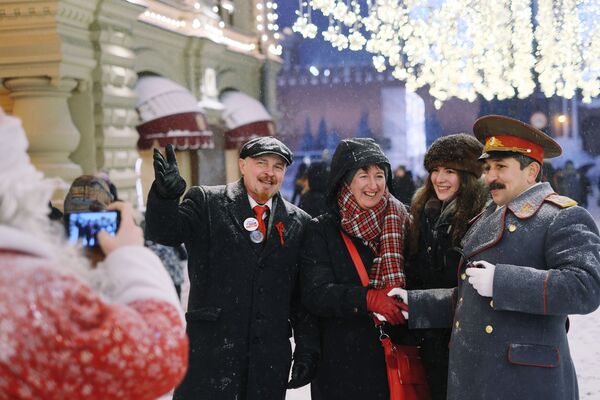 Туристы на Никольской улице в Москве фотографируются с мужчинами в костюмах В. И. Ленина и И. В. Сталина во время снегопада