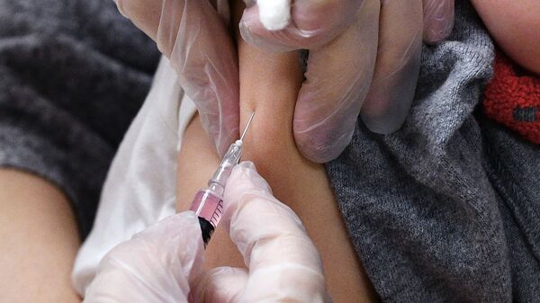 Медицинская сестра делает прививку от кори ребенку в детской поликлинике
