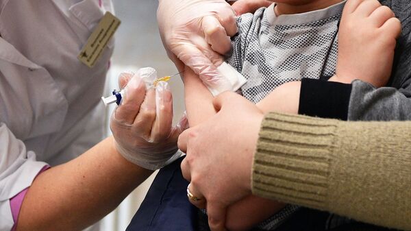 Медицинская сестра делает прививку ребенку в детской поликлинике