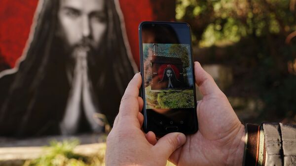 Мужчина фотографирует на смартфон граффити с изображением рэп-исполнителя Децла в Сочи 