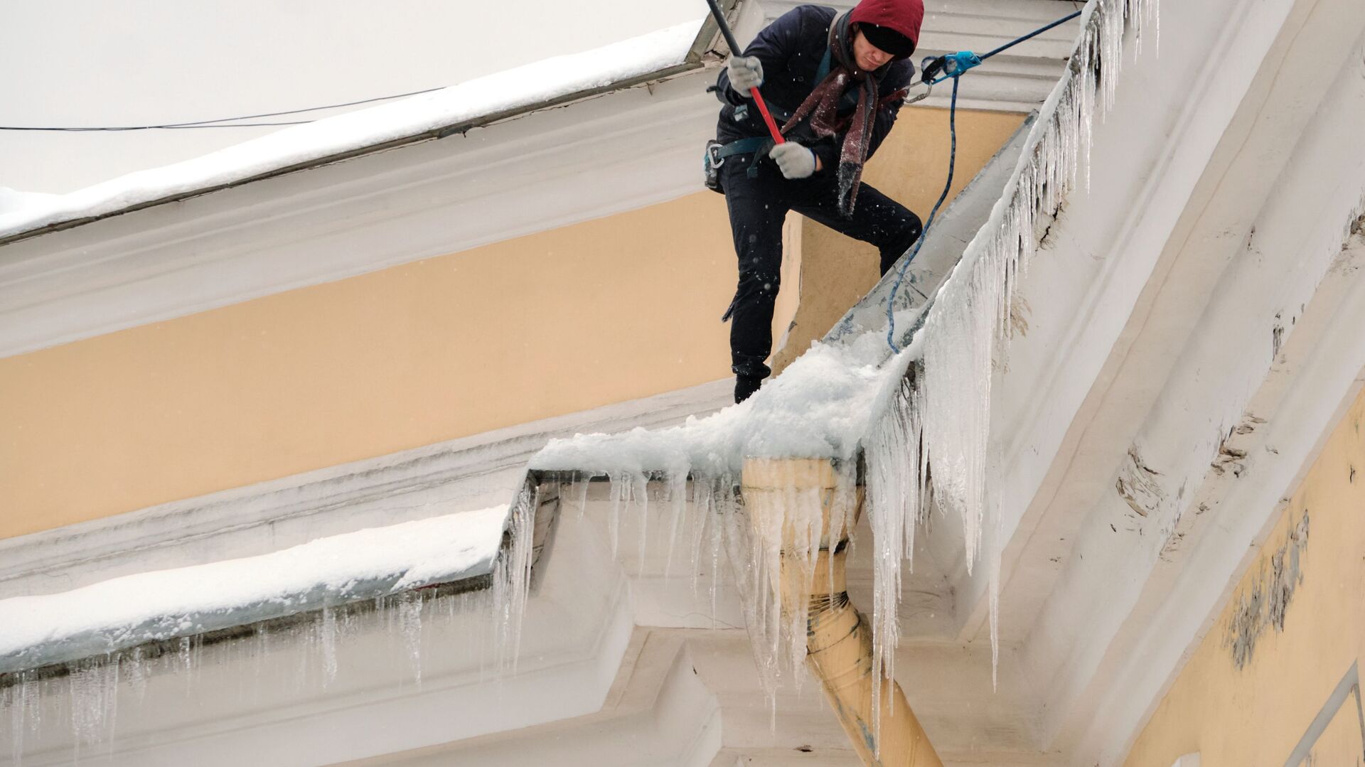 Работник коммунальной службы чистит от снега и сосулек крышу дома - РИА Новости, 1920, 14.02.2022