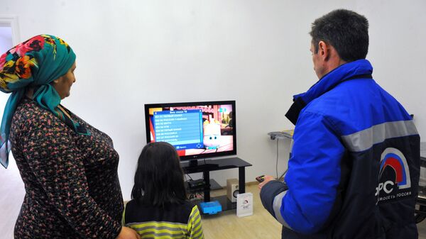 Инженер настраивает приставку цифрового телевидения в одном из жилых домов в Гудермесе