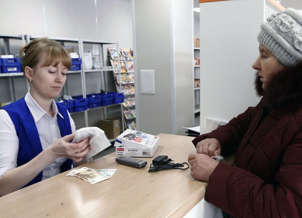 Оператор отделения почтовой связи в городе Гаврилов Ям упаковывает купленную жительницей города приставку для цифрового эфирного телевидения