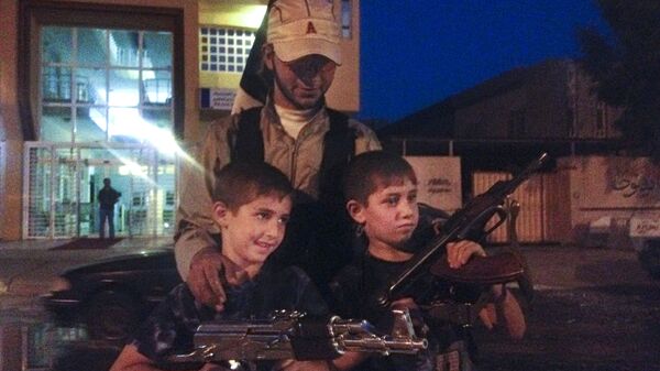 Боец ИГ* (деятельность запрещена в РФ) фотографируется с детьми, держащими оружие, в Ираке