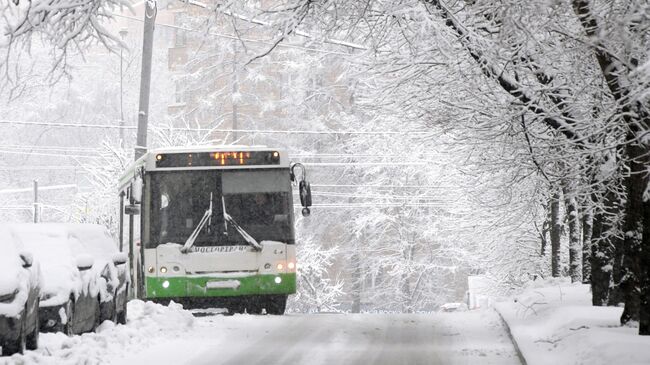 Автобус движется по заснеженной улице в Москве