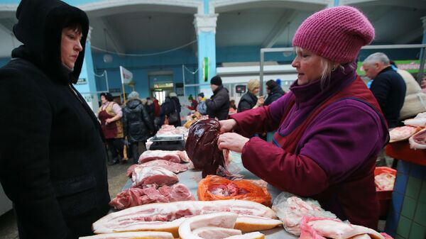 Покупательница выбирает мясо на продовольственном рынке в Киеве