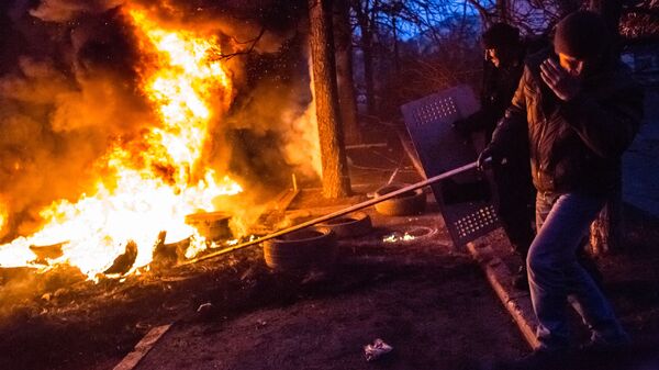 Сторонники оппозиции подбрасывают шины в огонь на баррикаде в Киеве