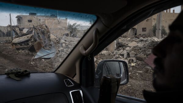 Бойцы Сирийских демократических сил (СДС) проезжают мимо разрушенных домов в деревне Аль-Сузах, в провинции Дейр-эз-Зор