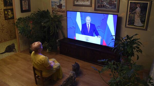 Жительница Владивостока смотрит телевизионную трансляцию ежегодного послания президента РФ Владимира Путина к Федеральному собранию