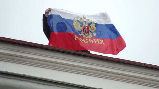 Местный житель с российским флагом на крыше Горсовета в Севастополе