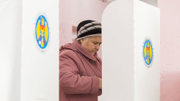 Женщина голосует на парламентских выборах на избирательном участке в Кишиневе