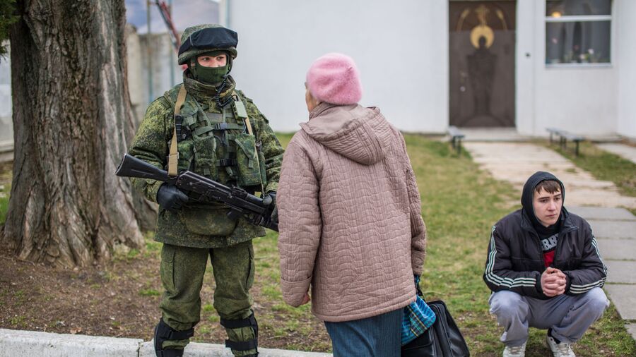 Местная жительница разговаривает с военнослужащим в селе Перевальное недалеко от Симферополя