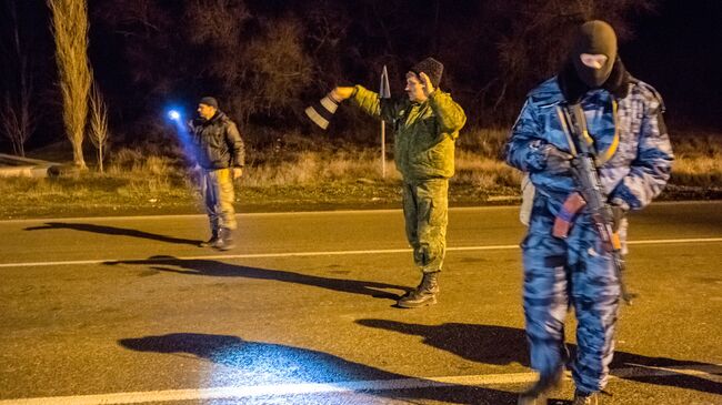 Сотрудник подразделения милиции специального назначения Беркут и казаки-добровольцы на блокопосту на въезде в Крым в районе Армянска