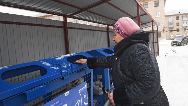 Женщина выбрасывает мусор в баки для раздельного сбора отходов в Московской области