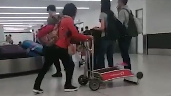 Женщина с тележкой в аэропорту Сиднея