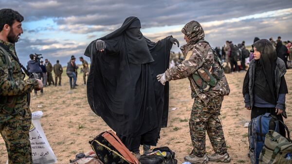 Боец Сирийских демократических сил проверяют женщину в деревне Багуз провинции Дейр-эз-Зор