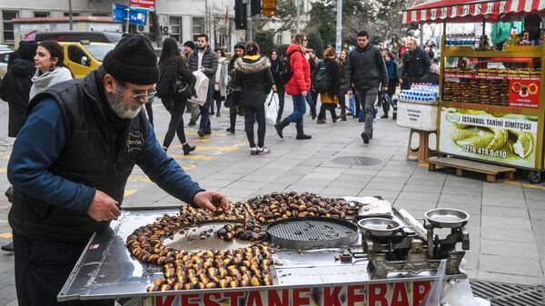 Мужчина продает жареные каштаны на одной из улиц Стамбула